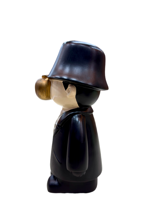 side view of 9.5 inch resin figurine with black coat, bucket hat, golden apple face and gold dollar chain, quirky home décor collectible