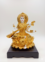 Gold-colored statue of a deity on a black base against a white background