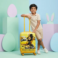 Boy aged 6 to 10 standing next to yellow 20 inch Bumblebee hard shell kids trolley bag with spinner wheels