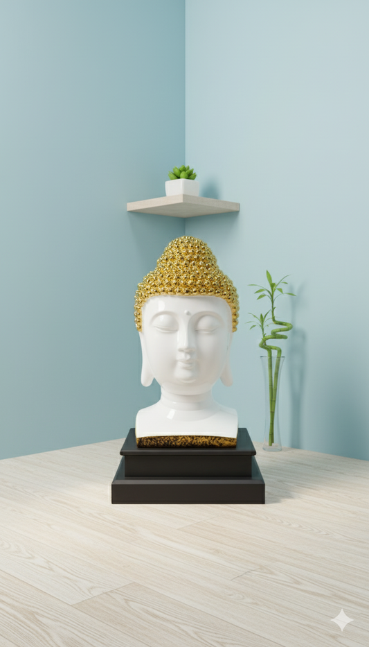 Buddha head sculpture with gold hair on a black base against a light blue wall.