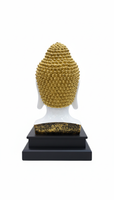 Buddha head statue with gold hair and white face on a black base 