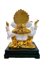 Gold and white statue on a black base with a white background