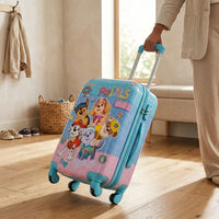 Adult pulling pink and blue 20 inch Paw Patrol hard shell kids trolley bag with teal spinner wheels indoors