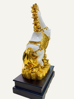 Gold and white decorative figure on a black base against a white background